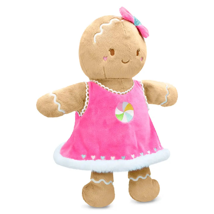 Plush toy gingerbread girl in a pink dress with a candy design on a white background
