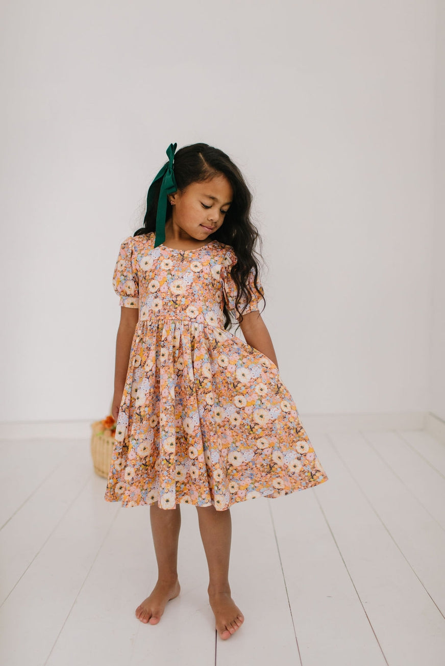 Young girl wearing a floral dress on a white floor and background