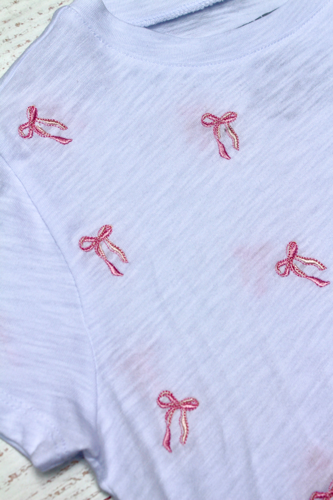 White ribbed sweater with red embroidered bows on a textured background