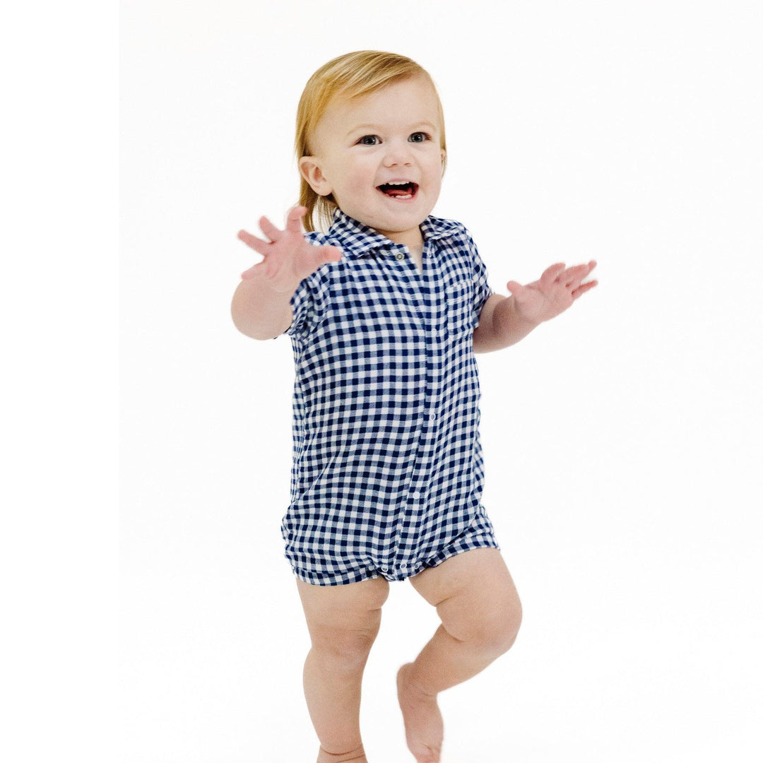 little baby modeling the navy and white gingham romper with collar and pocket. 
