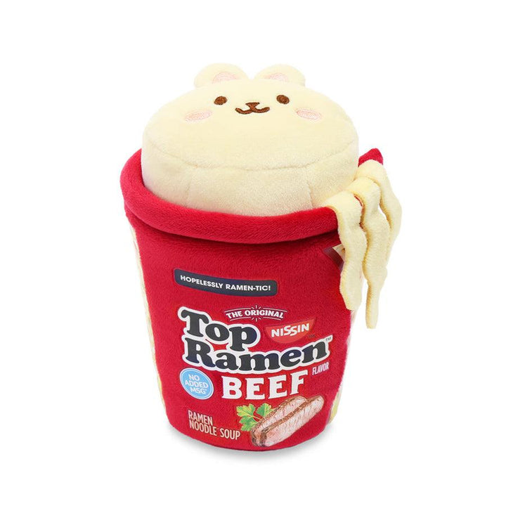 plush bunny sitting in a Beef flavor Ramen Cup. Ramen Cup is red with some noodles hanging out. 