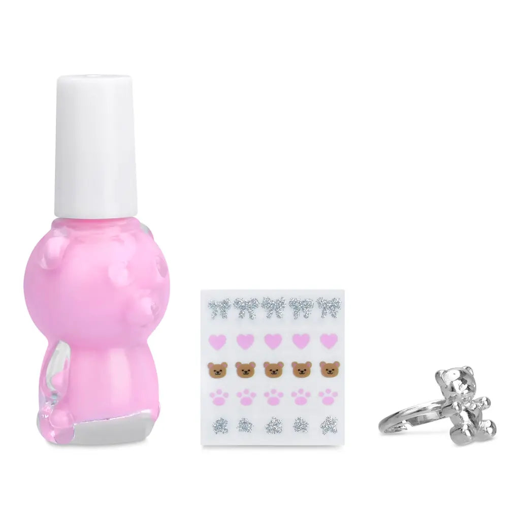 Pink nail polish bottle, teddy bear earrings, and silver ring on a white background