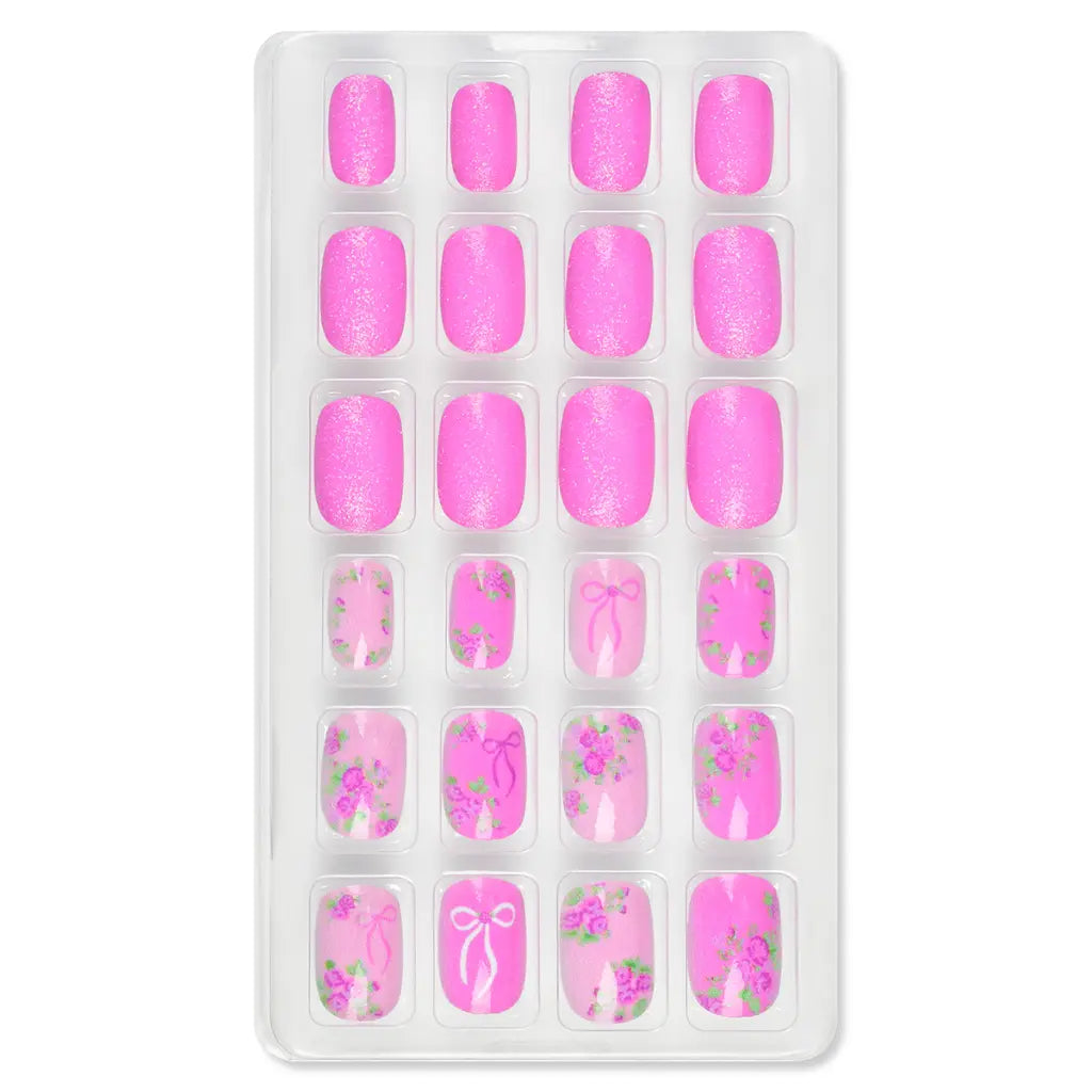 Tray of pink nail art designs with floral and bow patterns on a white background
