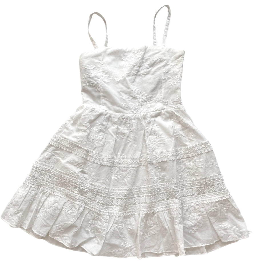 white dress with spaghetti straps. stripes of lace along skirt. white embroidery all over the bodice of the dress. 
