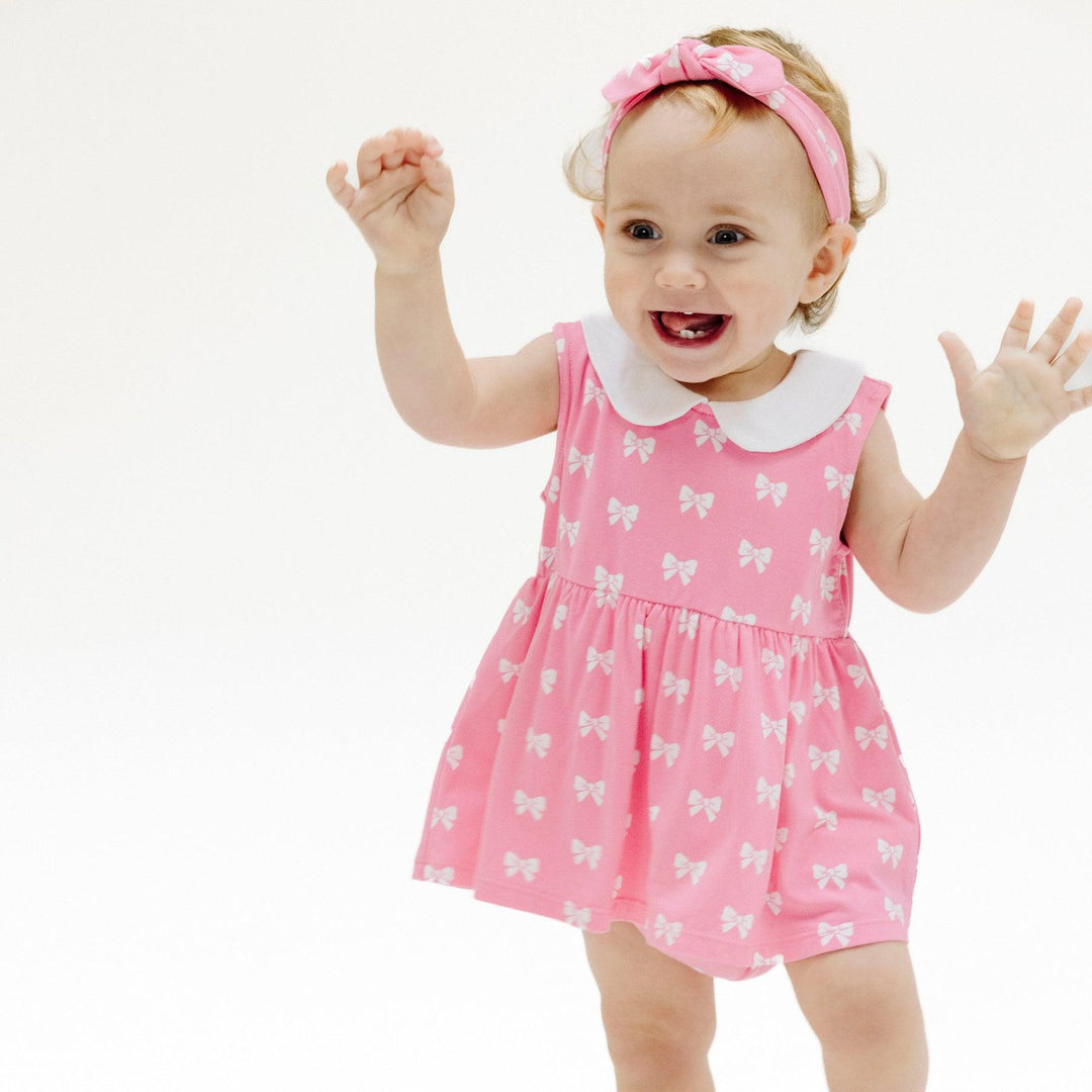 baby modeling the pink dress with bubble and peter pan collar. the dress hits mid thigh