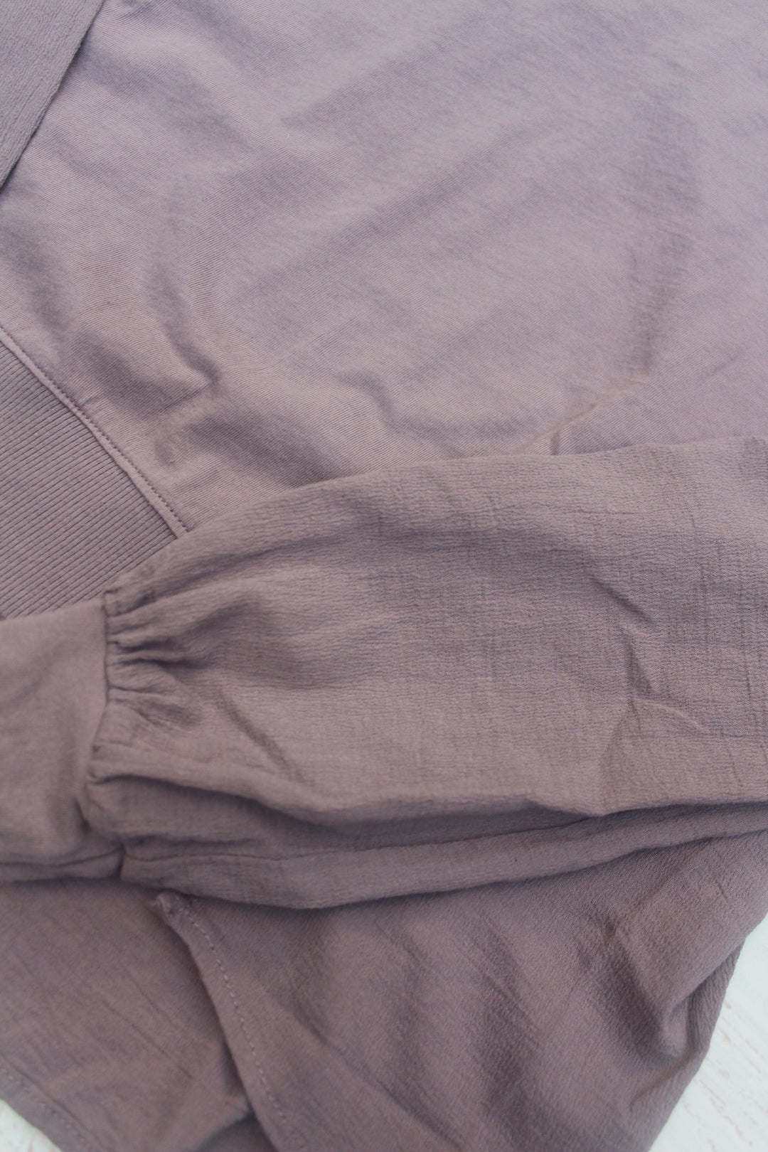 Close-up of purple/gray sleeve of the sweatshirt with a textured fabric pattern.