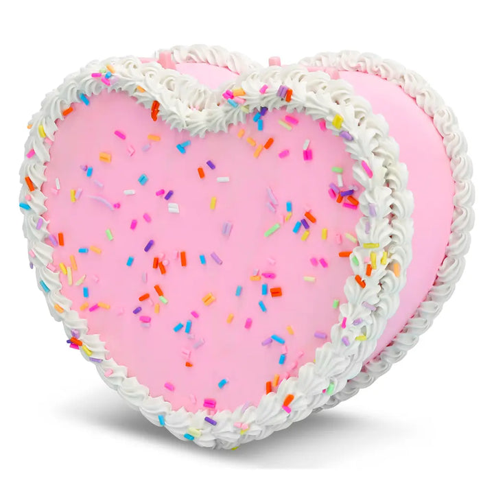 Heart-shaped pink cake with white frosting and colorful sprinkles on a white background