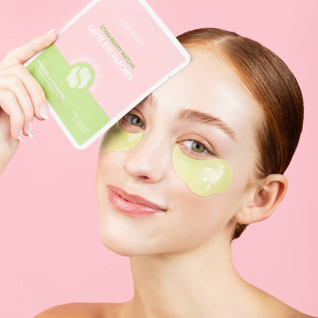 Woman wearing green eye patches with a pink background