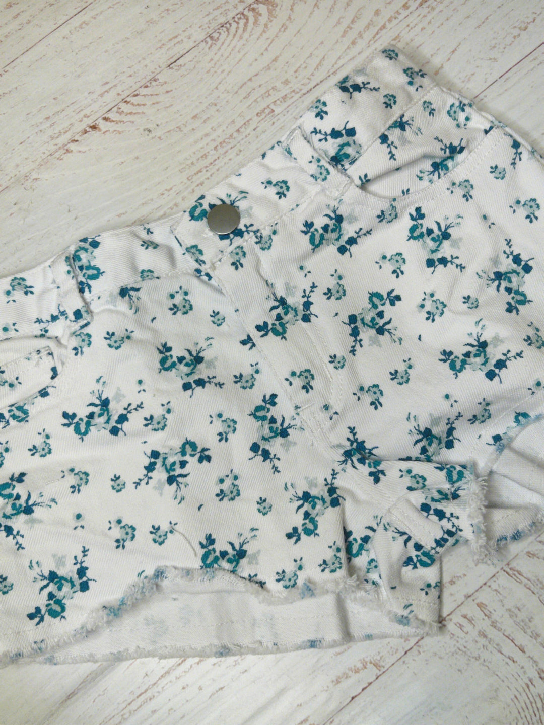 white twill cut off shorts with button and pockets. the floral print is blue and navy roses and tiny rosebuds all over. 