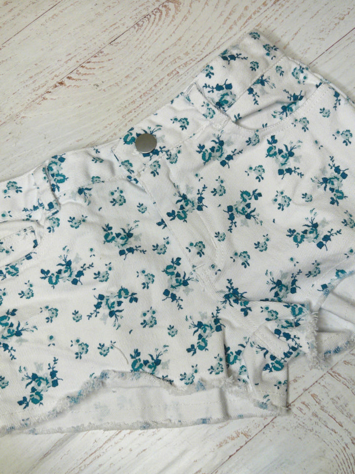 white twill cut off shorts with button and pockets. the floral print is blue and navy roses and tiny rosebuds all over. 