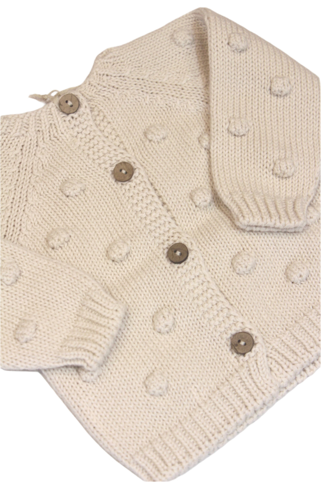 creme sweater with buttons down one side and a crew neck sweater with no buttons on the other side. baby sweater has pom poms  on it. 