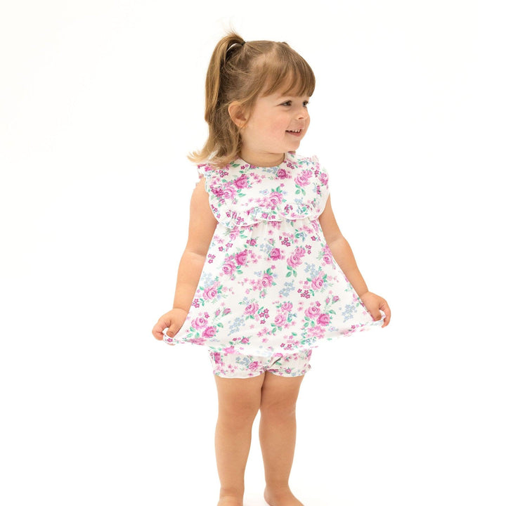 little girl modeling the two piece set, white with purple cabbage rose print. ruffled top