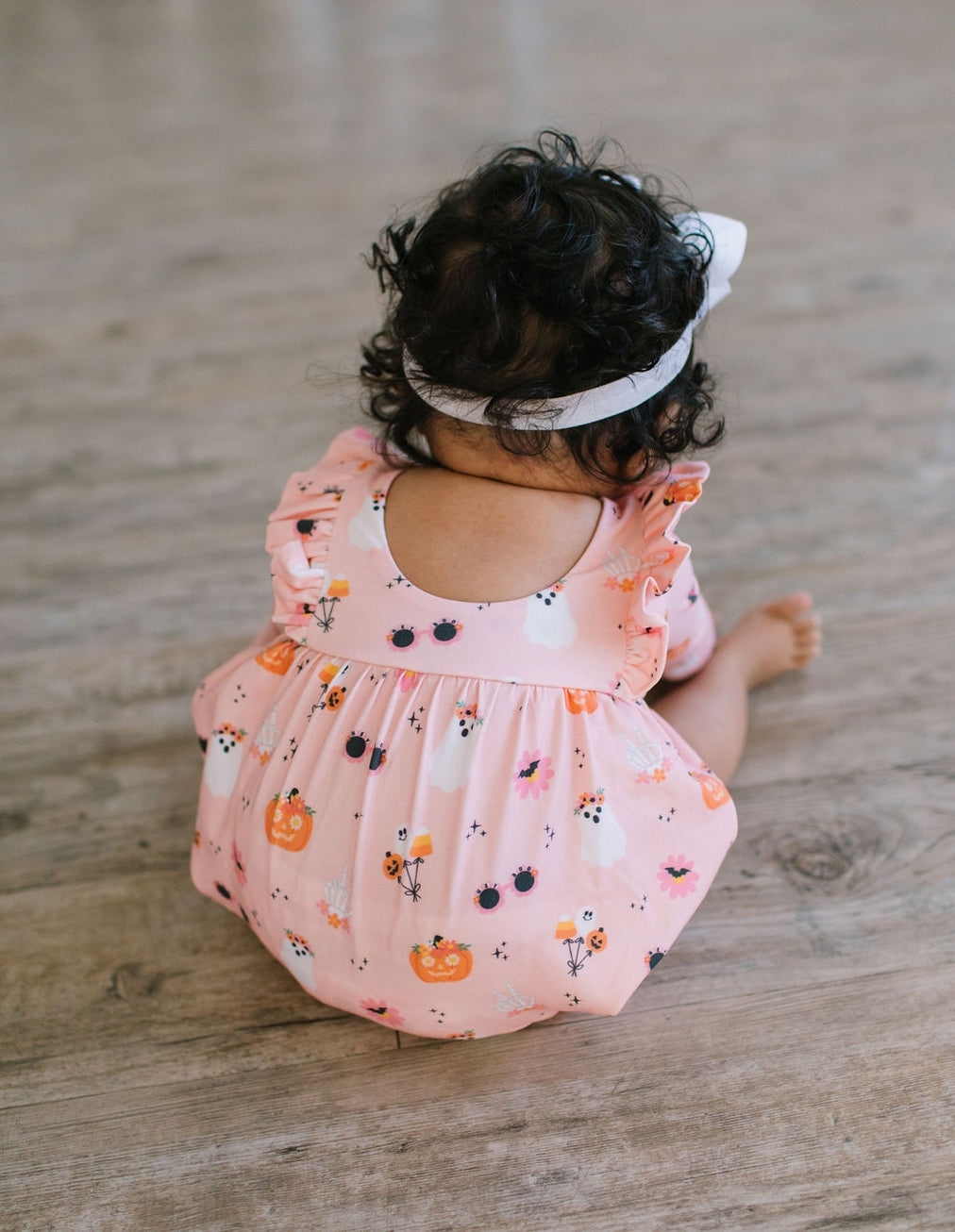 back of Baby in a pink floral romper, scoop back. halloween print