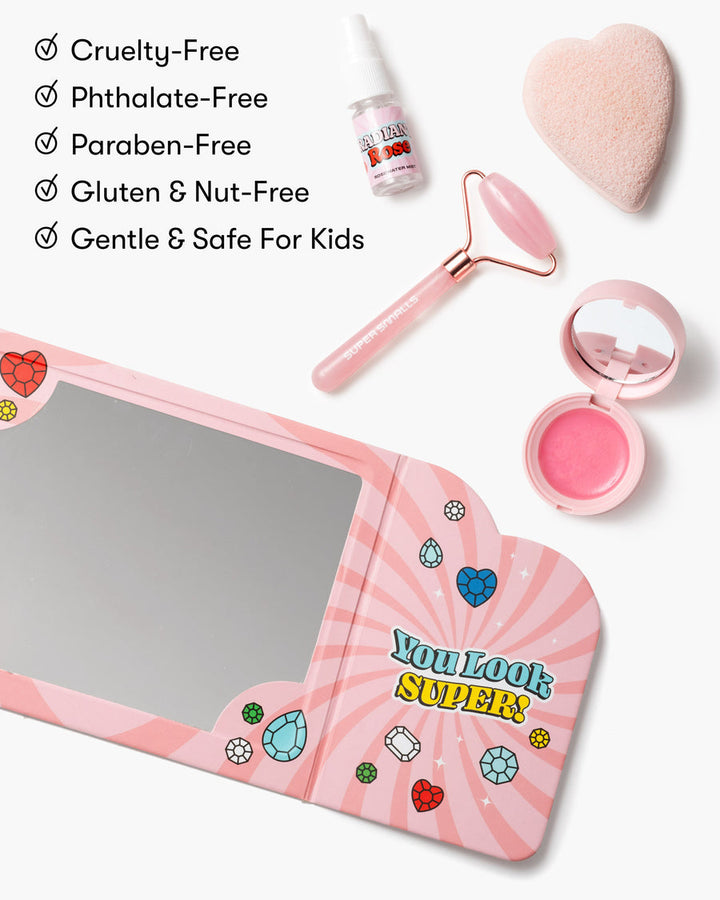 Pink heart-shaped mirror with cosmetic tools on a white background, featuring cruelty-free and safe-for-kids text.