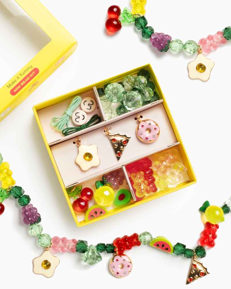 picture of bead kit with beads charms and cord to make bracelets and necklaces. The theme of the kit is yummy food