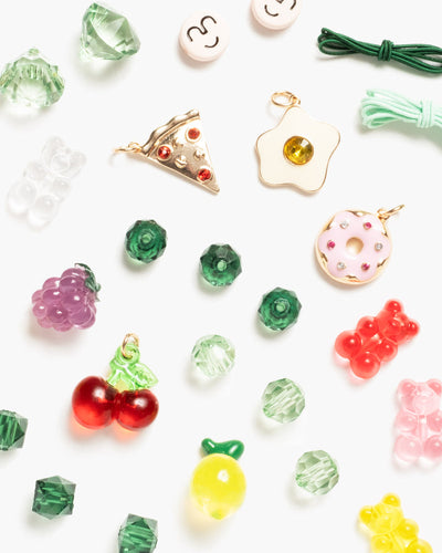 different selection of beads and charms in the kit including multi colored beads and charms like pizza and doughnuts