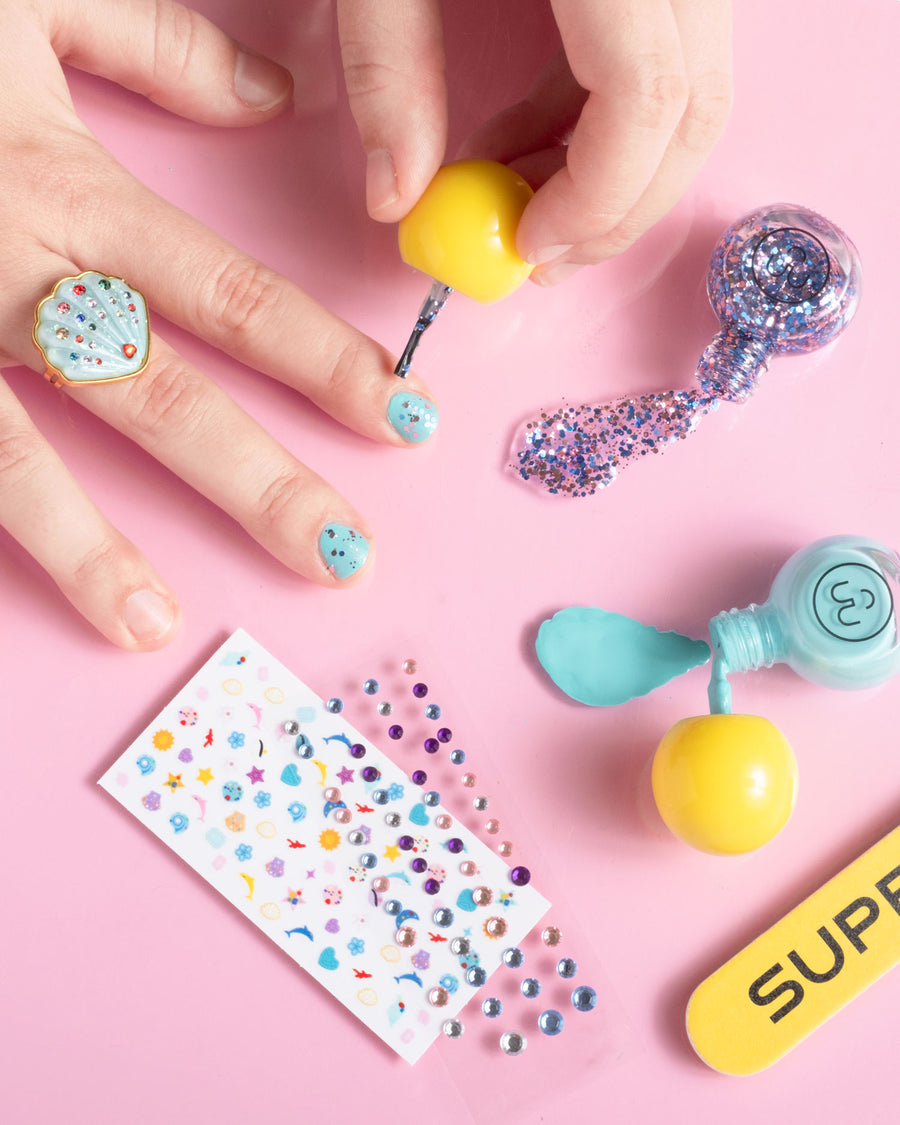 Colorful nail art tools and stickers on a pink background