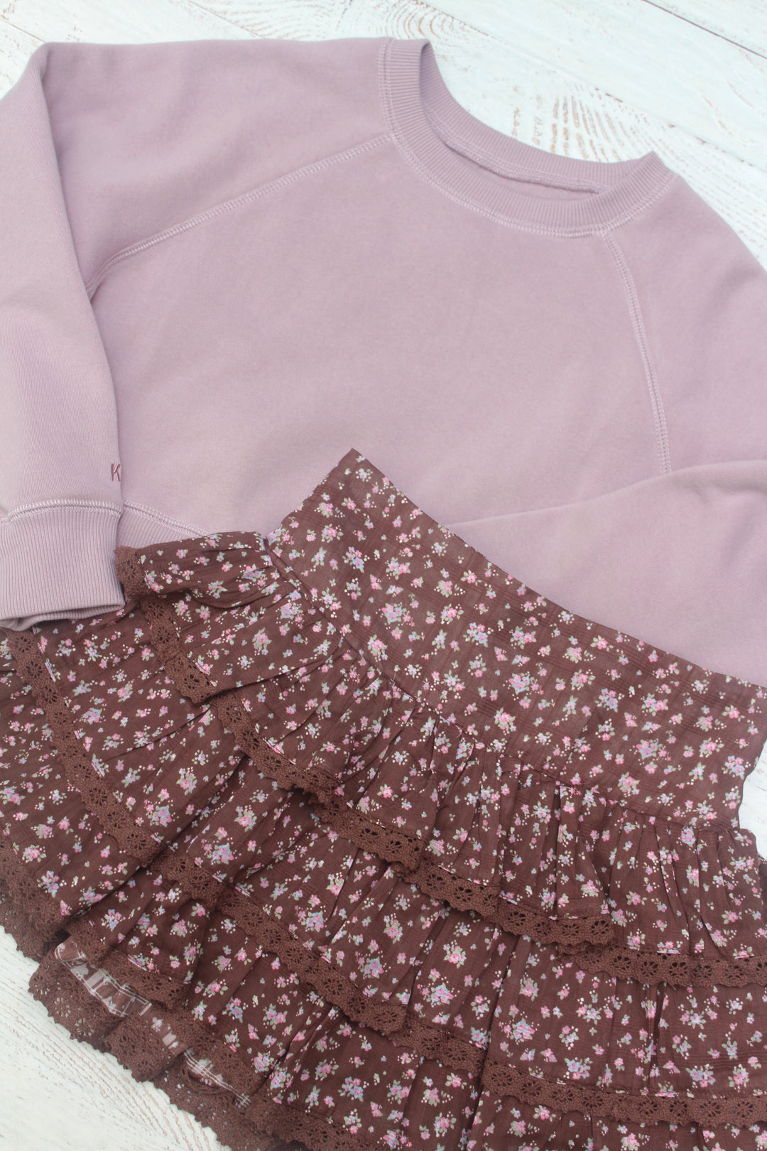 Light purple sweatshirt and brown floral skirt on a white surface