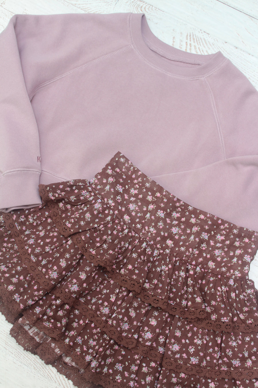 Light purple sweatshirt and brown floral skirt on a white surface