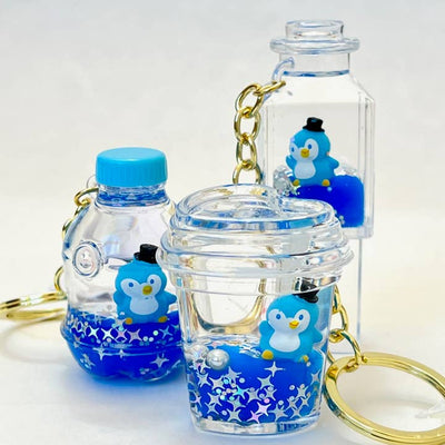 floaty keychains with blue water inside and a penguin wearing a hat