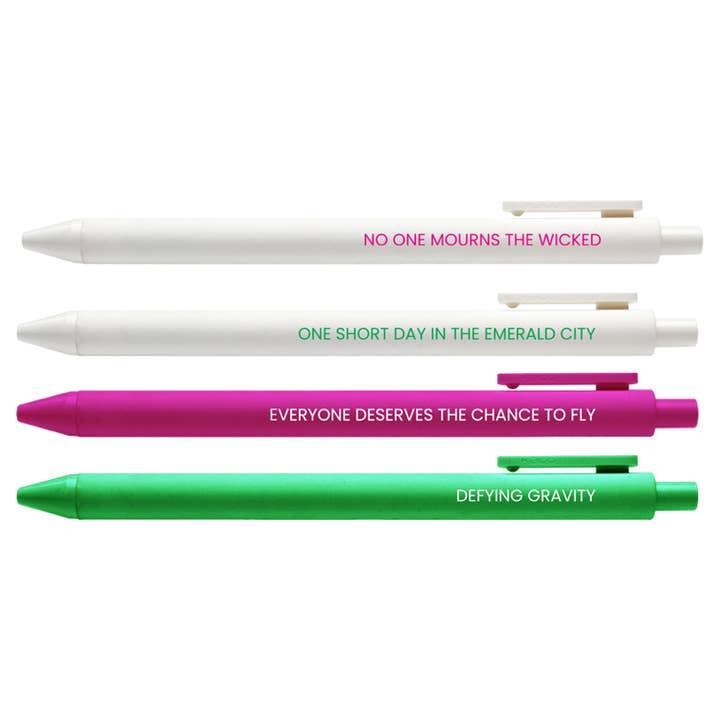 close up of the pen set in the wicked theme: pink, white and green pens with different sayings from the movie on them: Defying Gravity, everyone deserves a chance to fly, one short day in the emerald city and no one mourns the wicked. 