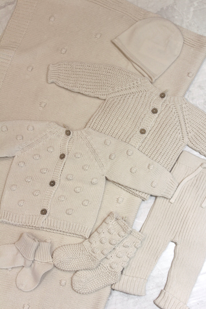 knit baby collection in the same color and fabrication: textured cardigans, knit pants, socks, booties and blanket. 