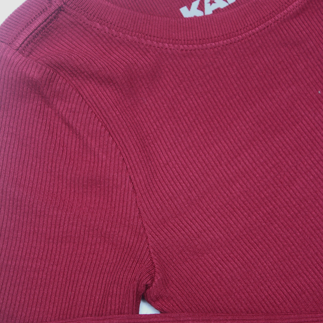 Close-up of a maroon shirt with a brand logo on the collar.