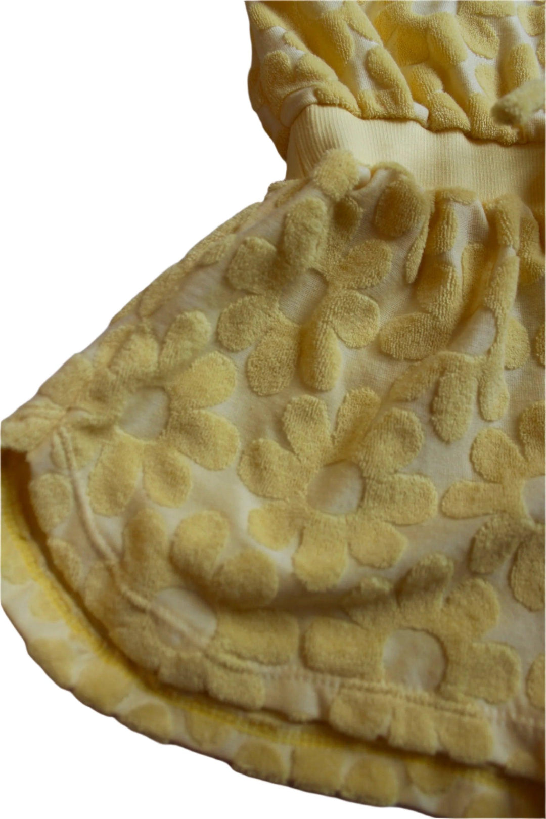 close up of the terry cloth daisy romper with daisy embossing on it. yellow color