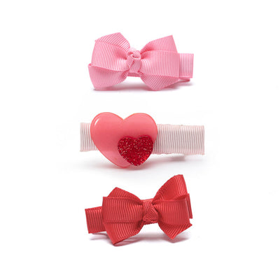 2 clips with grograin ribbon bows and one with a pink heart and a smaller red glitter heart off to the side. 