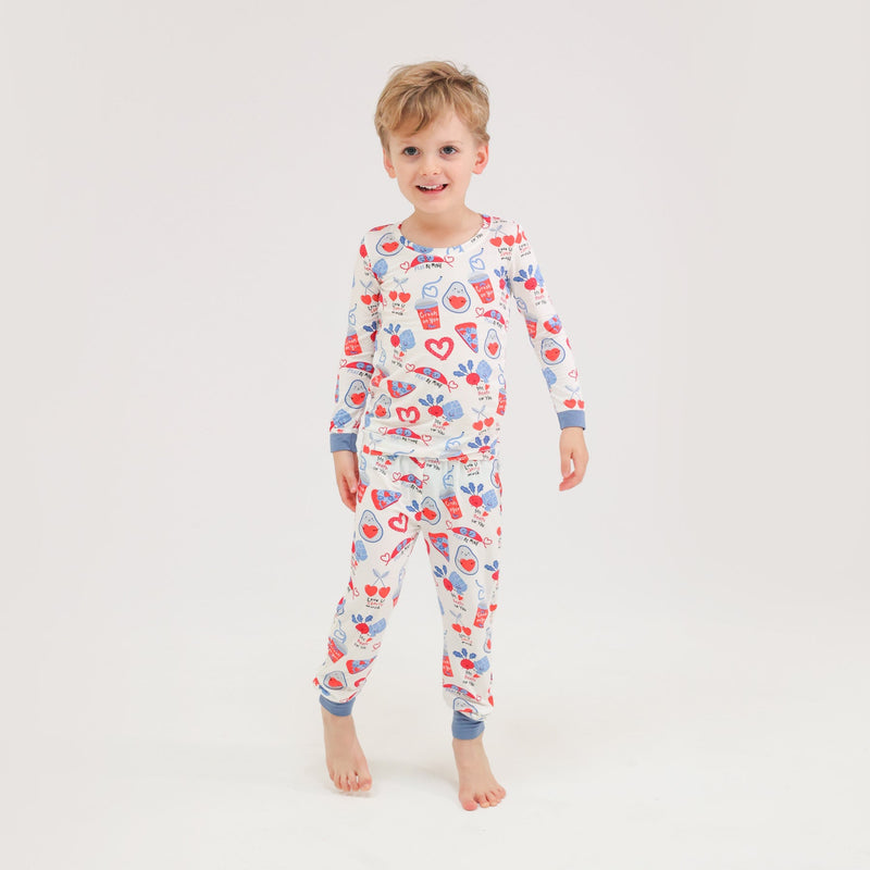 little boy modeling the valentines day pajamas and foodie print with smiling food holding hearts