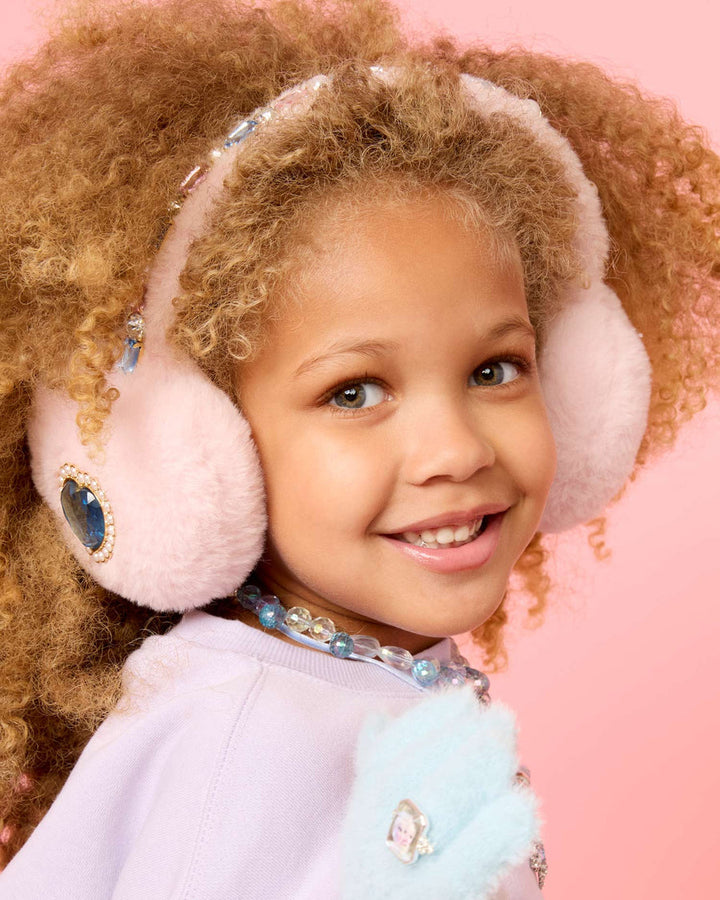 Child wearing pink earmuffs with decorative stones on a pink background