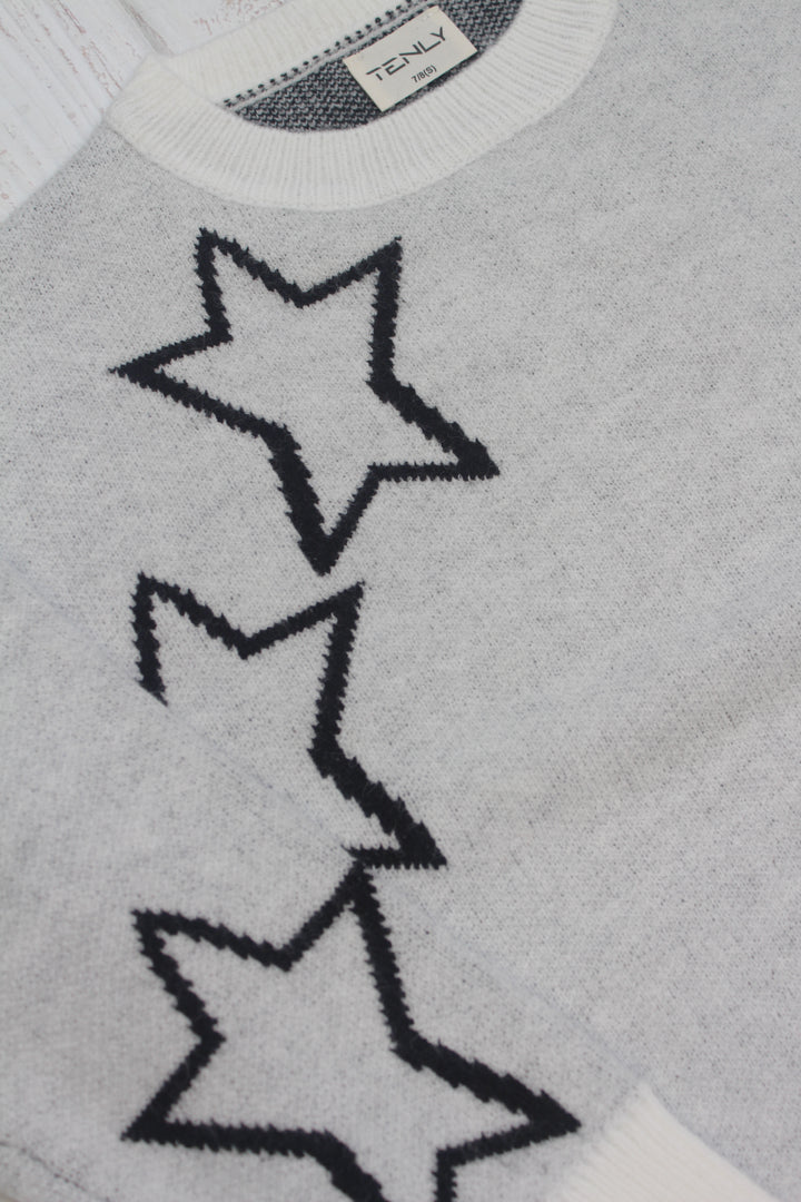 Gray sweater with star patterns and a brand label on a gray background