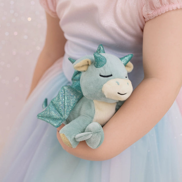 Child holding a plush dragon toy with glittery accents against a soft, blurred background.