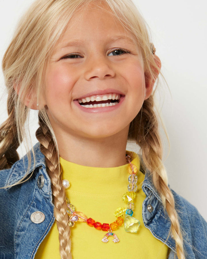 Child wearing a colorful necklace with a plain background