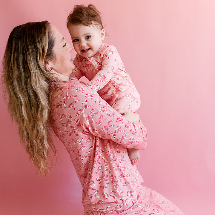 Woman and child wearing matching pink candy cane outfits against a pink background