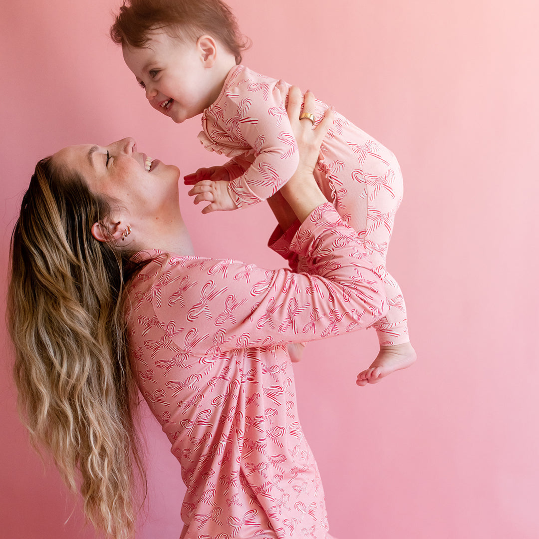 Woman and child in matching pink outfits against a pink background