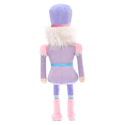 this picture is of the nutcracker plush standing from behind. you can see his fuzzy hair and purple outfit