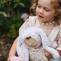 little girl carrying the bunny doll in a doll carrier . 