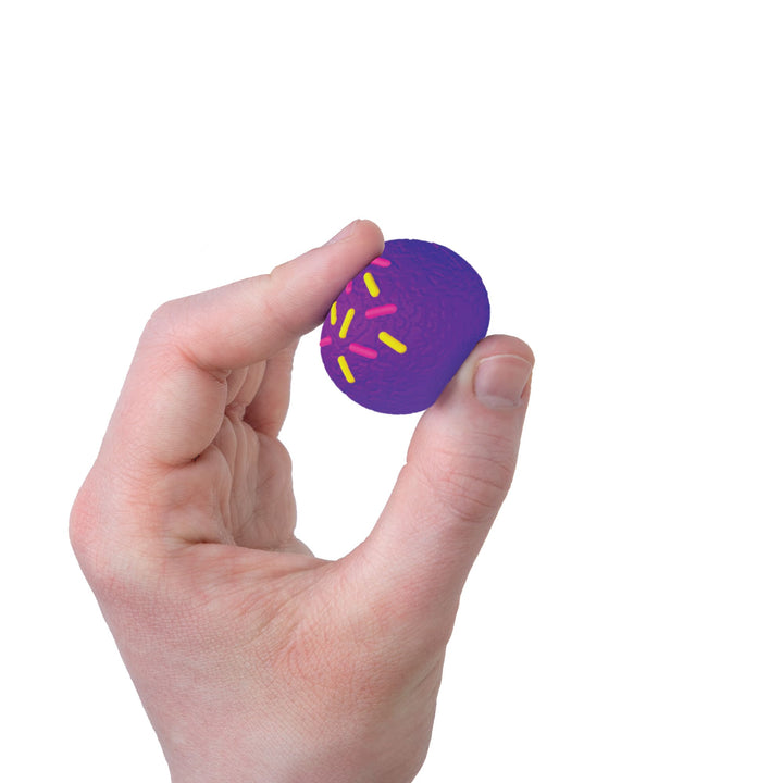 Hand holding a purple circle with yellow sprinkles on a white background