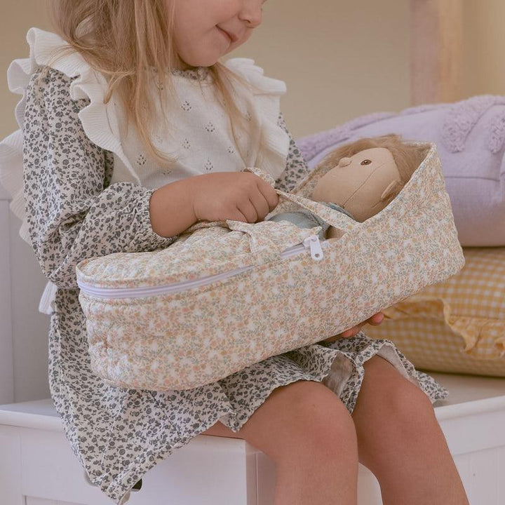 little girl playing with a dinkum and baby doll in the carrycot. 