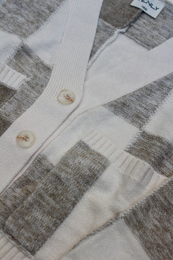 Close-up of a patterned cardigan with buttons and a brand tag.