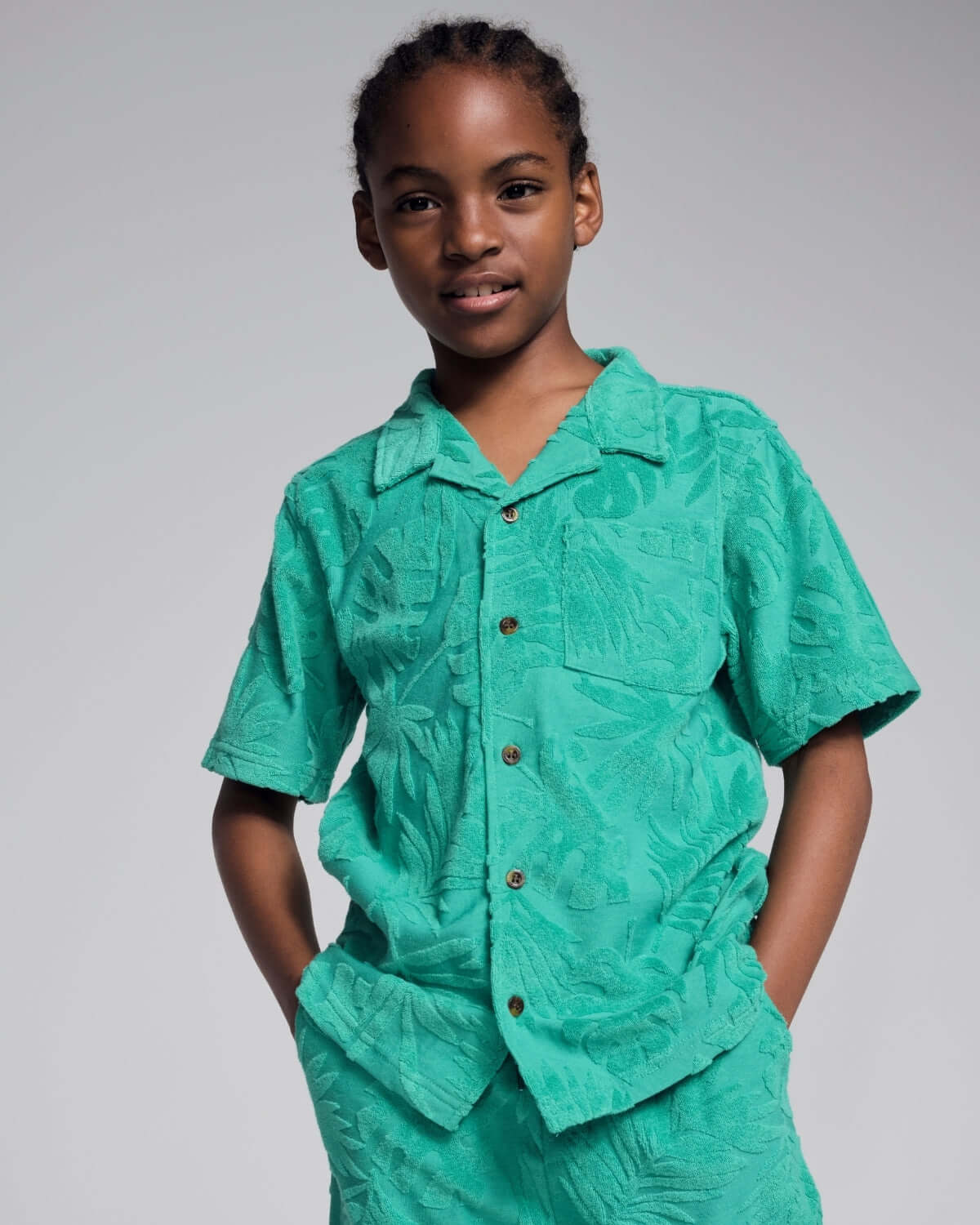 Person wearing a teal patterned outfit on a plain background