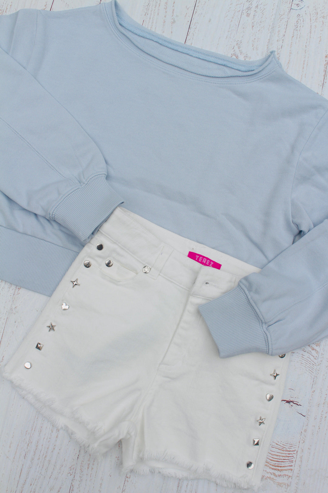 baby blue sweatshirt with white cut off shorts and silver studs along the sides of the shorts. 