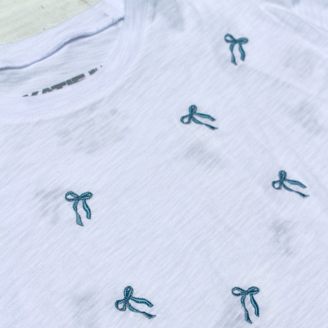White fabric with blue embroidered bows on a textured surface