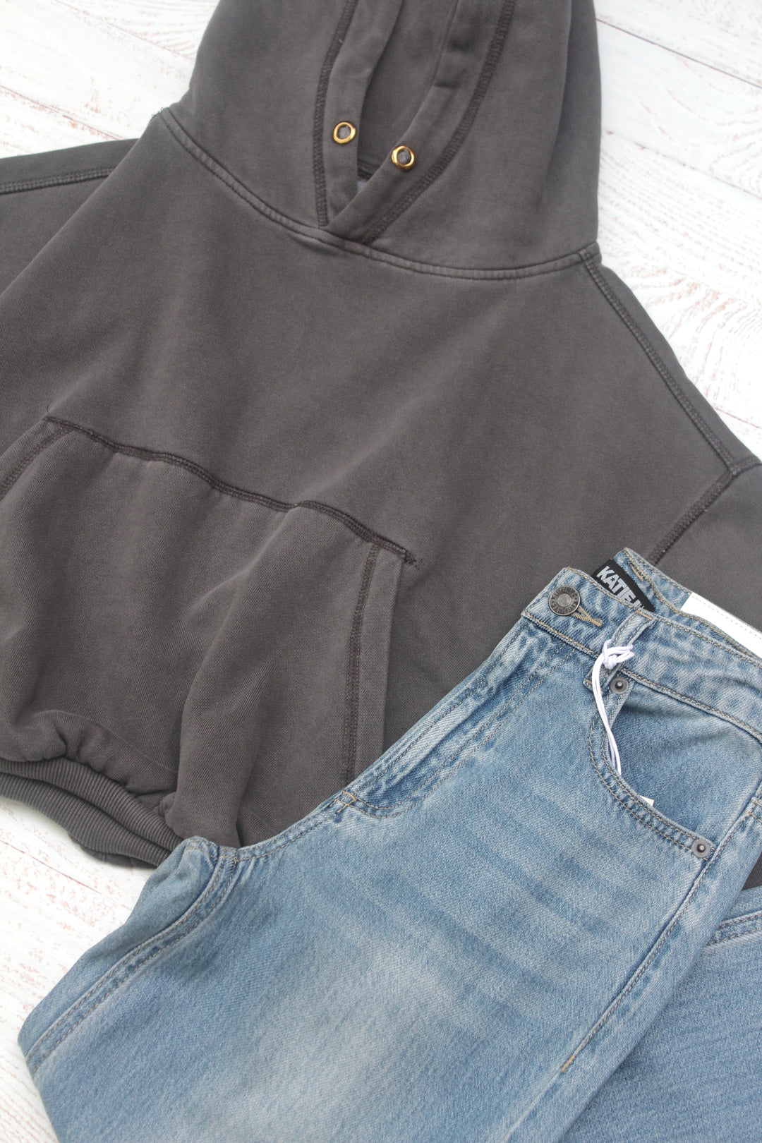 Gray hoodie and blue jeans on a white surface