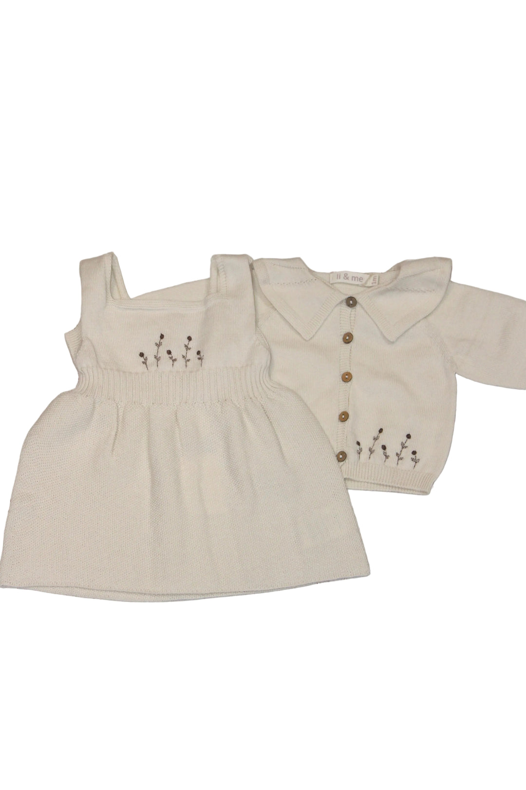 Beige baby dress and cardigan set on a wooden surface