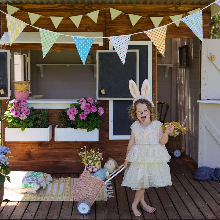 little girl playing with flowers and a luggy while wearing fluffy ink bunny ears. 