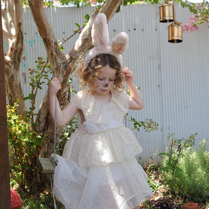little girl wearing a beautfiul dress playing on a swing and wearing the fluffy bunny ears