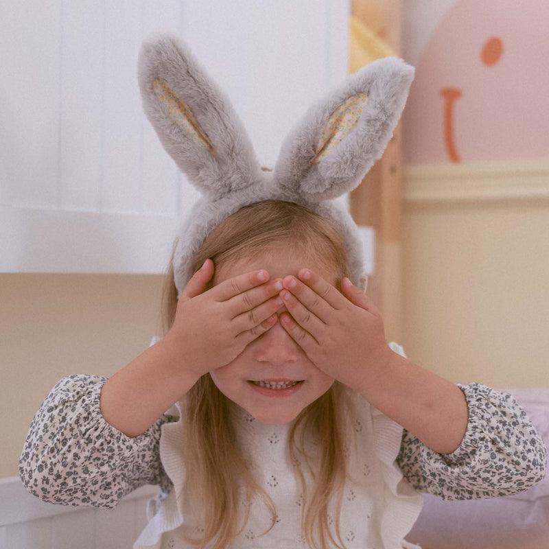 little girl covering her eyes wearing bunny ears 