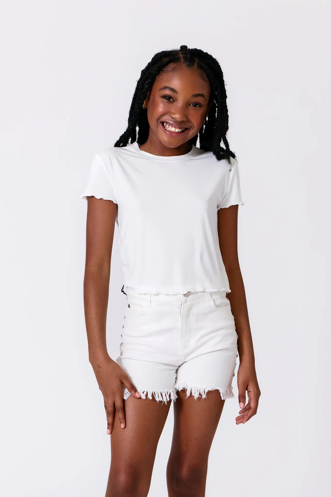 girl modeling a white tee and white cut off shorts with metal studs on the sides. 
